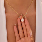 Gold necklace with a diamond pendant on a person's hand against a neutral background