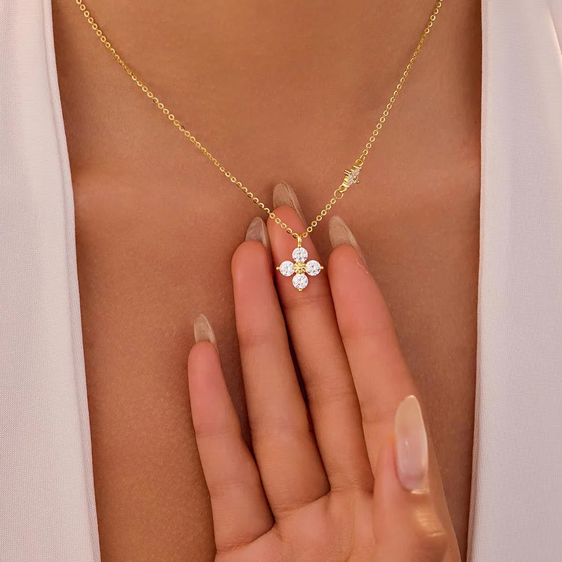 Gold necklace with a diamond pendant on a person's hand against a neutral background